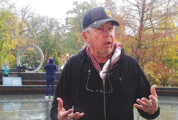 Harvey Pratt, designer of the National Native American Veteran Memorial, speaks with reporters on Nov. 11 at the Museum of the American Indian. The memorial can be seen in the distance over his shoulder. Jessie Christopher Smith/Gaylord News