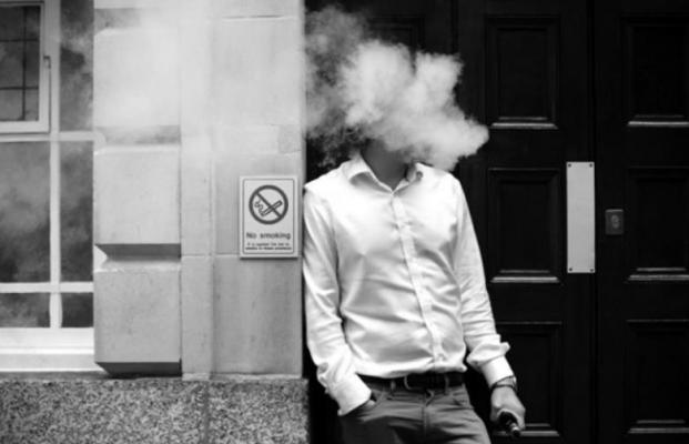 A smoker is engulfed by vapours as he smokes an electronic vaping machine during lunch time in central London on August 9, 2017. (Tolga Akmen/ AFP/Getty Images/TNS)