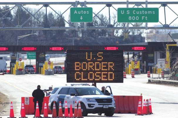 U.S. Customs officers stand beside a sign saying that the U.S. border is closed at the at Lansdowne, Ontario, on March 22, 2020. (Lars Hagberg/AFP via Getty Images/TNS)