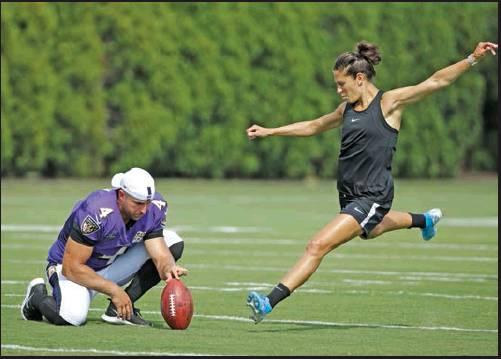 BALTIMORE RAVENS Sam Koch holds the ball for United States soccer player Carli Lloyd as she attempts to kick a field goal after the Philadelphia Eagles and the Baltimore Ravens held a joint NFL football practice in Philadelphia Aug. 20. Could Lloyd have a career in the NFL? (AP Photo)
