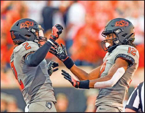 OKLAHOMA STATE wide receiver Tylan Wallace, left, celebrates with fellow wide receiver Jordan McCray after scoring a touchdown during a college football game against McNeese in Stillwater Saturday. The Cowboys travel to play cross-state rival Tulsa this week. (AP Photo)
