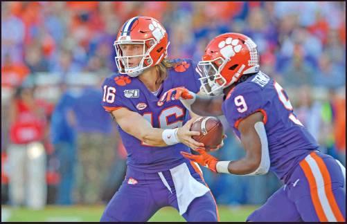 CLEMSON’S TREVOR Lawrence, left, hands the ball off to Travis Etienne during a Nov. 2 football game against Wofford in Clemson, S.C. Clemson, the defending national champion, didn’t make the top four in the first playoff ranikings Tuesday. (AP Photo)