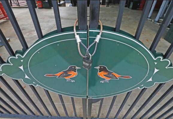 LOCKED GATES and empty walkways are shown at Oriole Park at Camden Yards, home of the Baltimore Orioles baseball team, on what was to be opening day March 26 in Baltimore, Md. If the season is played, it could last until December. (AP Photo)