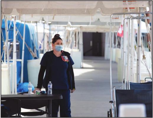 A NURSE waits at the emergency room entrance at OU Medical Center on March 28 where patients are being evaluated before entering the building. (Whitney Bryen/Oklahoma Watch)