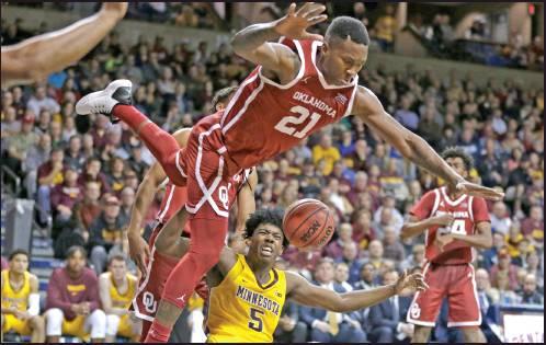KRISTIAN DOOLITTLE (21) of Oklahoma loses his balance while defending against Minnesota’s Marcus Carr (5) during a basketball game in Sioux Falls, S.D., Saturday. The Sooners won 71-62. (AP