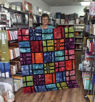 THOMASINE HENDRICKSON displays a quilt at her store, The Quilt Barn. There are plenty of other quilts and other merchandise available for those who love to craft quilts. (Photos by Everett Brazil, III)