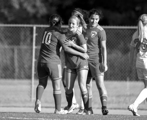 Josie Jarvis (middle) receives congratulations from her teammates after scoring a goal. (photo by John Pickard/Northern Oklahoma College).