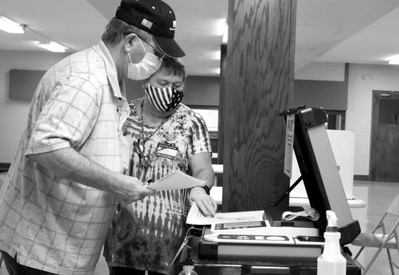 Ottawa County precinct worker Kay Boman Harvey helps Ronnie Barnes feed his ballots into the voting machine at the Miami Civic Center in this 2020 file photo. Ottawa County, located in Oklahoma’s northeast corner, gets its TV news from the Joplin, Mo. market. It ranked 74th among the state’s 77 counties for voter turnout, with less than half of its registered voters casting a ballot in the 2022 gubernatorial election. (Kaylea Hutson-Miller/For Oklahoma Watch)