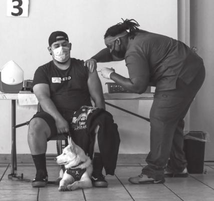 Joel Jurez, 22, holds hid dog Yuki as medical assistant Adrian Davis administers a COVID-19 vaccine at a vaccination clinic at St. Patrick’s Catholic Church on April 9, 2021, in Los Angeles. (Irfan Khan/Los Angeles Times/TNS)