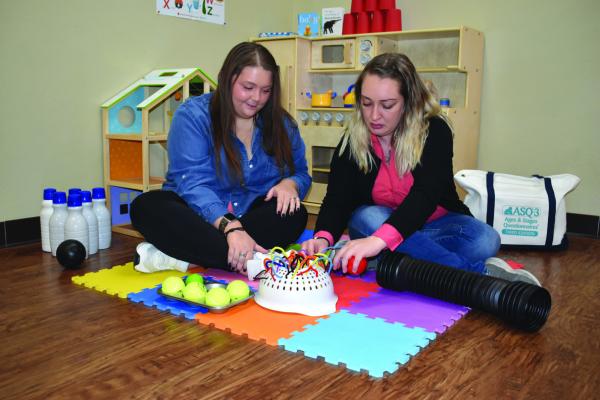 NOELLE BRIEN, left, and Lynn Robinson show the use of toys and games in working with children in the Parents as Teachers program at Northern Oklahoma Youth Services. The program helps parents teach their kids concepts before they enter pre-k and kindergarten. (Photo by Everett Brazil, III)