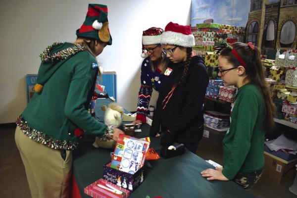 KAREN DEAKINS, center, helps youth ‘elves’ as they assist Christmas shoppers at Newkirk’s Children’s Christmas Shop Dec. 9. The 2023 event was the biggest in more than 20 years. (Photo by Everett Brazil, III)