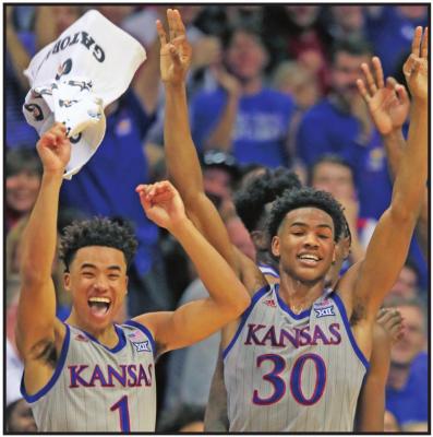 KANSAS GUARDS Devon Dotson (1) and Ochai Agbaji (30) celebrate a teammate’s three-point basket during a November game against Monmouth in Lawrence, Kan. Kansas finished the season No. 1 in The Associated Press college basketball poll, receiving 63 of 65 first-place votes from a national media panel Wednesday. (AP Photo)