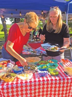 Nancy Shepard and Ellen Cobb add toppings to the hamburger for their hobo dinners.