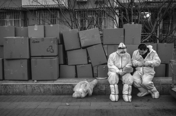 Epidemic control workers wear PPE to protect against the spread of COVID-19 as they look at a list outside a building with apartments where people who have tested positive are doing home quarantine on Dec. 5, 2022, in Beijing. In recent weeks, Chinese authorities eased COVID testing requirements amid elevated cases and public protests. (Kevin Frayer/Getty Images/TNS)