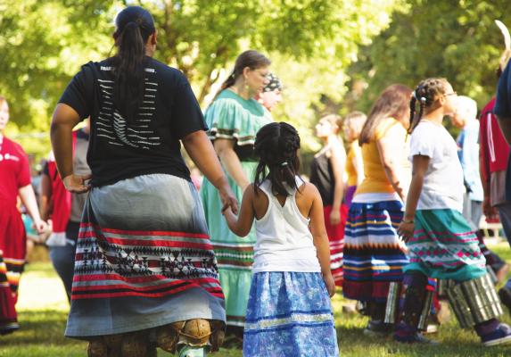 A MUSCOGEE (Creek) mother and daughter from Oklahoma wait to join a stomp dance at the Ocmulgee Mounds National Historical Park in Macon, Ga. The Muscogee homelands spanned Alabama and Georgia before removal to Indian Territory. A celebration is held annually at the park, which is a sacred site featuring Mississippian-era mounds. Photo provided by Muscogee (Creek) Nation.