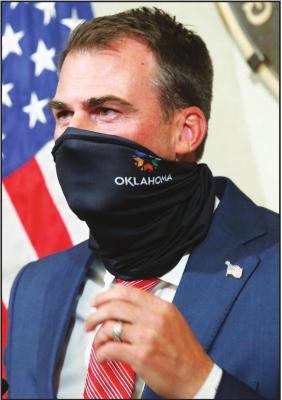 OKLAHOMA GOV. Kevin Stitt demonstrates how easy it is to wear a face mask during a news conference, Tuesday, June 30, 2020, in Oklahoma City. (AP Photo)
