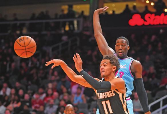 ATLANTA HAWKS guard Trae Young (11) passes as Miami Heat forward Bam Adebayo defends during an NBA game Thursday in Atlanta. Young had his first 50-point game in the NBA. (AP Photo)