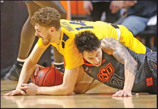 WEST VIRGINIA guard Chase Harler (14) and Oklahoma State guard Lindy Waters III (21) reach for the ball in a basketball game in Stillwater Monday. West Virginia won the game 55-41. (AP Photo)