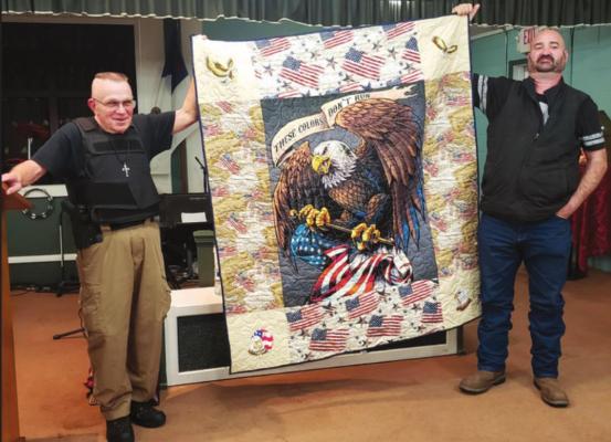 Terry Thompson (left) and Brian Hobbs (right) holding the quilt made and donated by Sherry Jeffries. (Photo by Darlene Engelking)