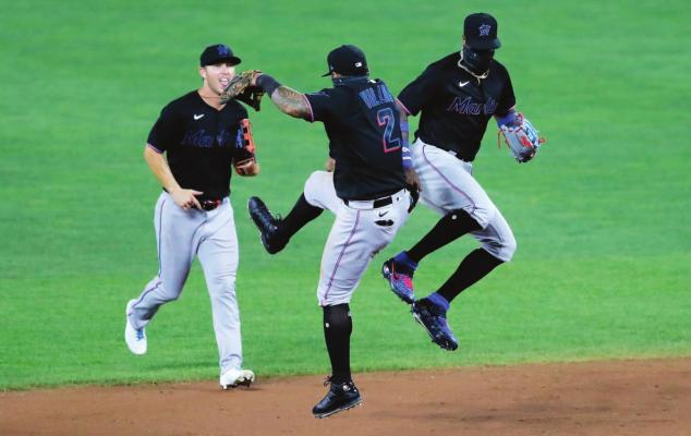 MIAMI MARLINS shortstop Jonathan Villar (2) and center fielder Monte Harrison, right, celebrate after defeating the Baltimore Orioles 2-1 in the second game of a doubleheader, Wednesday, Aug. 5, 2020, in Baltimore. Marlins’ Corey Dickerson, left, looks on. (AP Photo/Julio Cortez)