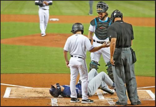 CHRISTIAN YELICH of the Milwaukee Brewers’lies on the ground after an injury during an at-bat, as Miami Marlins catcher Jorge Alfaro, rear, home plate umpire Kerwin Danley and a bat boy stand next to him. Yelich broke a knee cap after being hit by his own foul ball Tuesday in Miami. He will miss the rest of the regular season. (AP Photo)