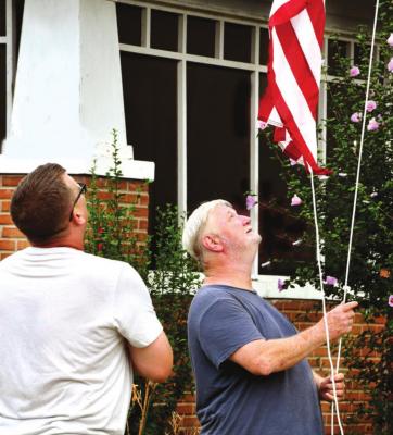 Danny Dodson raising the United States flag, with Roy Powell, Vice President of the Flag Poles Honoring Our Veterans NW Chapter, family and friends saying the Pledge of Allegiance. (Photo by Dianna Kuhn, Whimsicalm Photography)