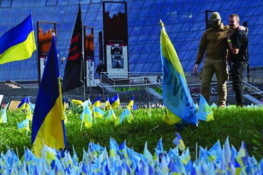A SERVICEMAN and his friend pay tribute to their comrades next to the Ukrainian flags for fallen soldiers, on the Independence Square in Kyiv, on Oct. 30, 2023, amid the Russian invasion of Ukraine. (Sergei Supinsky/AFP/Getty Images/TNS)