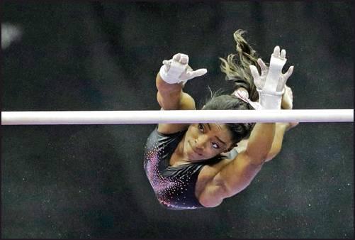 SIMONE BILES practices on the uneven bars for the senior women’s competition at the 2019 U.S. Gymnastics Championships Sunday in Kansas City, Mo. (AP Photo)