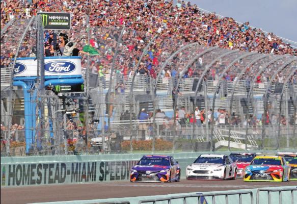 DENNY HAMLIN, left, leads the pack at the start of the 2018 NASCAR Cup Series championship auto race at Homestead-Miami Speedway, in Homestead, Fla. NASCAR and IndyCar have each suspended their races for a time. Instead NASCAR has been running virtual races. (AP Photo)