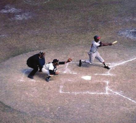 HENRY AARON is shown batting in the 1957 World Series against the New York Yankees. Here he is hitting one of three home runs he hit during the event. Yogi Berra is the Yankee catcher.