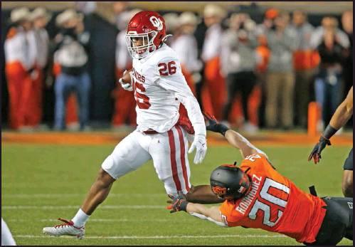 OKLAHOMA RUNNING back Kennedy Brooks (26) avoids a tackle by Oklahoma State safety Malcolm Rodriguez (20) in the fist half of a football game in Stillwater Saturday. The Sooners won 34-16. (AP Photo)