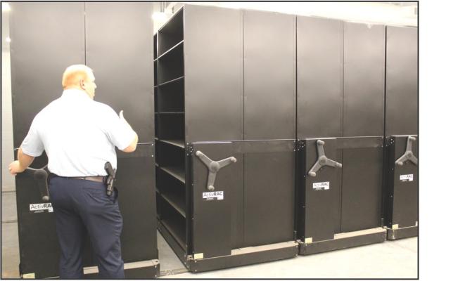 Chief Bohon demonstrates the high-density shelving in the evidence locker, which saves space and solves many problems for long-term evidence storage. (Photo by Calley Lamar)