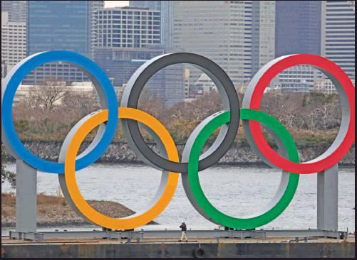 A WORKER is dwarfed by the Olympics Rings on a barge Friday in the Odaiba district of Tokyo. (AP Photo)