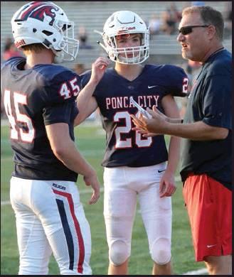 PONCA CITY Wildcat football players Kaden Jefferies (45) and Shayden Trant (26) are in a huddle with Assistant Coach Casey Love during Thursday’s scrimmage against Perkins-Tryon at Sullins Stadium. This photo was provided by Larry Williams.