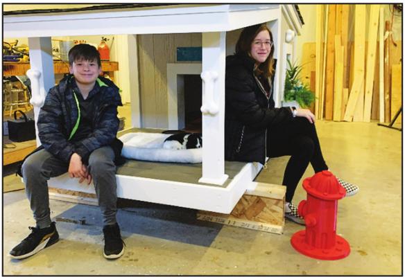THIS DOG house was constructed by Adam Leaming and his dad of the ''Leaming Rin Tin Renovators'' representing the University Center. The house will be one of the many items up for auction at Saturday night's fundraiser for the Northern Oklahoma Humane Society event at the Marland Mansion. Pictured are Annie and Sam Leaming.