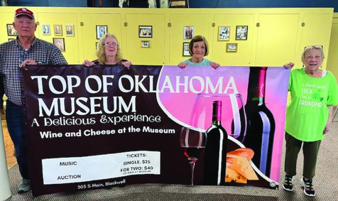 TOP OF Oklahoma Historical Society board members prepare for the April 6 “A Delicious Experience” wine and cheese event at the museum. Getting the advertising banner ready are, left to right, Jim Corbin, Sandy Compros , Marion Tucker and Janice Teske. (Photo provided)
