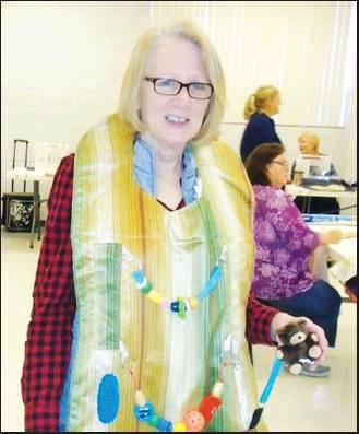 CATHY LESTER, Pioneer Area Quilters guild president models an example of a charity project the guild members create for local organizations. Pictured is a fidget apron for Alzheimers or dementia patients. Quilts of Valor and baby quilts for Living Hope Pregnancy Center are other items made for donation. The guild will meet at 9 a.m. on Monday, Jan. 6 at St. Paul’s United Methodist Church, 1904 N. Pecan in Ponca City for their annual charity work day.