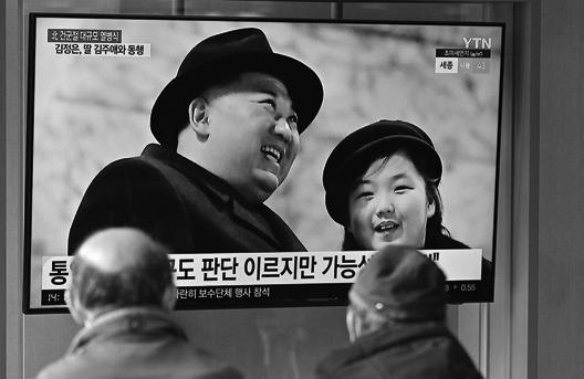 In this file photo from Feb. 9, 2023, people watch a television screen showing a news broadcast with an image of North Korean leader Kim Jong Un (left) and his daughter presumed to be named Ju Ae (right) attending a military parade held in Pyongyang to mark the 75th founding anniversary of its armed forces, at a railway station in Seoul. (Jung Yeon-Je/AFP via Getty Images/TNS)