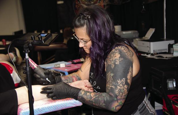 AN ARTIST focuses intently as she tattoos her client’s new piece. (Photo by Dailyn Emery)