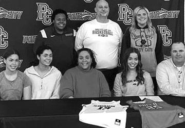 EMMA GERTKEN of Ponca City Tuesday signed a letter of intent to play basketball at Kansas Wesleyan University in Salina, Kan. Gertken, fourth from the left in front row above, led the Lady Cats in scoring during the recently completed season with an average of 14 points per game. At the signing were family members, front row, and back row from left, Coach Lauren Brown of Kansas Wesleyan, Jody Fincher, head Ponca City coach; and Mica Estrada, Ponca City assistant.