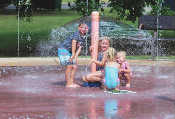 YOUNGSTERS TRY to stay cool on Wednesday by playing in the splash pad on Seventh Street. Temperatures are expected to hit 100 degrees by this weekend. (News Photo by Jessica Windom)